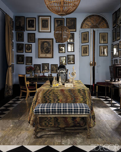 An 18th-century rug covers a table in the entrance hall; the bench is in the Régence style, the desk is by Marc du Plantier, and 18th-century engravings fill the walls.