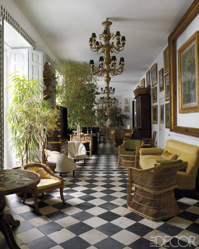 The gallery features 1960s Baguès chandeliers, a Napoleon III–style sofa, '50s rattan armchairs, and an 18th-century marble- and-slate-tile floor.
