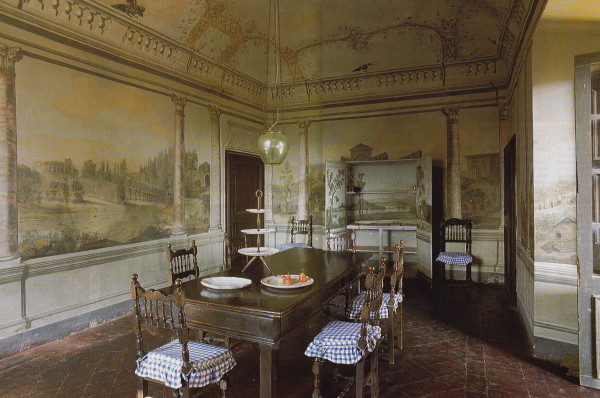 The frescoes in the dining room lend the feel of an orangery, with a rural landscape set beyond faux columns. A trellis entwined with morning glory frames the room at cornice height. At one end a cupboard is painted into the scenery. Photo by James Mortimer.