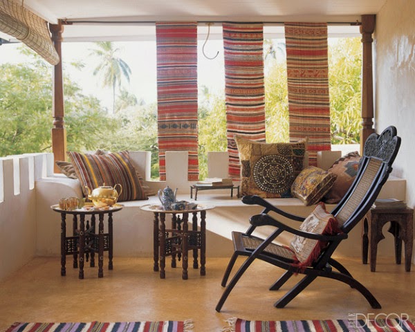 Marie-Paule Pellé enhanced the veranda of a home in Lamu, Kenya, with a Goanese chair and pillows from India and Pakistan; North African trays are set on Moroccan stools, and antique Vietnamese weavings provide shade. Photo by Pieter Estersohn for Elle Decor.
